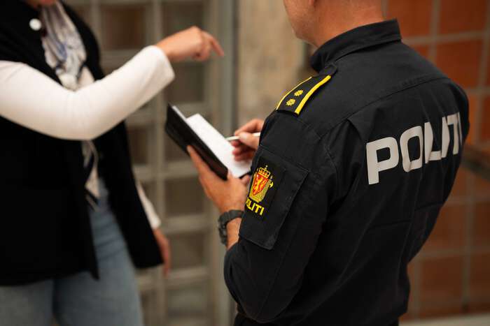 Bildet viser en politijenesteperson med notatblokk som snakker med en person.