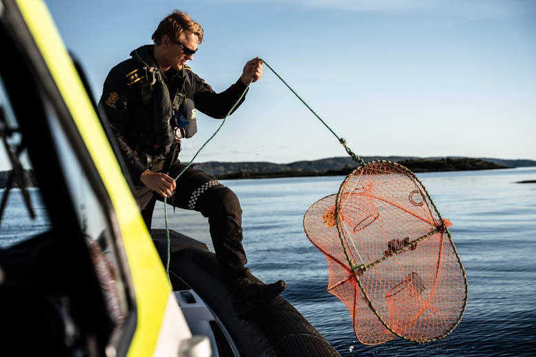 Mann i politiuniform på båt som holder i en hummertegn