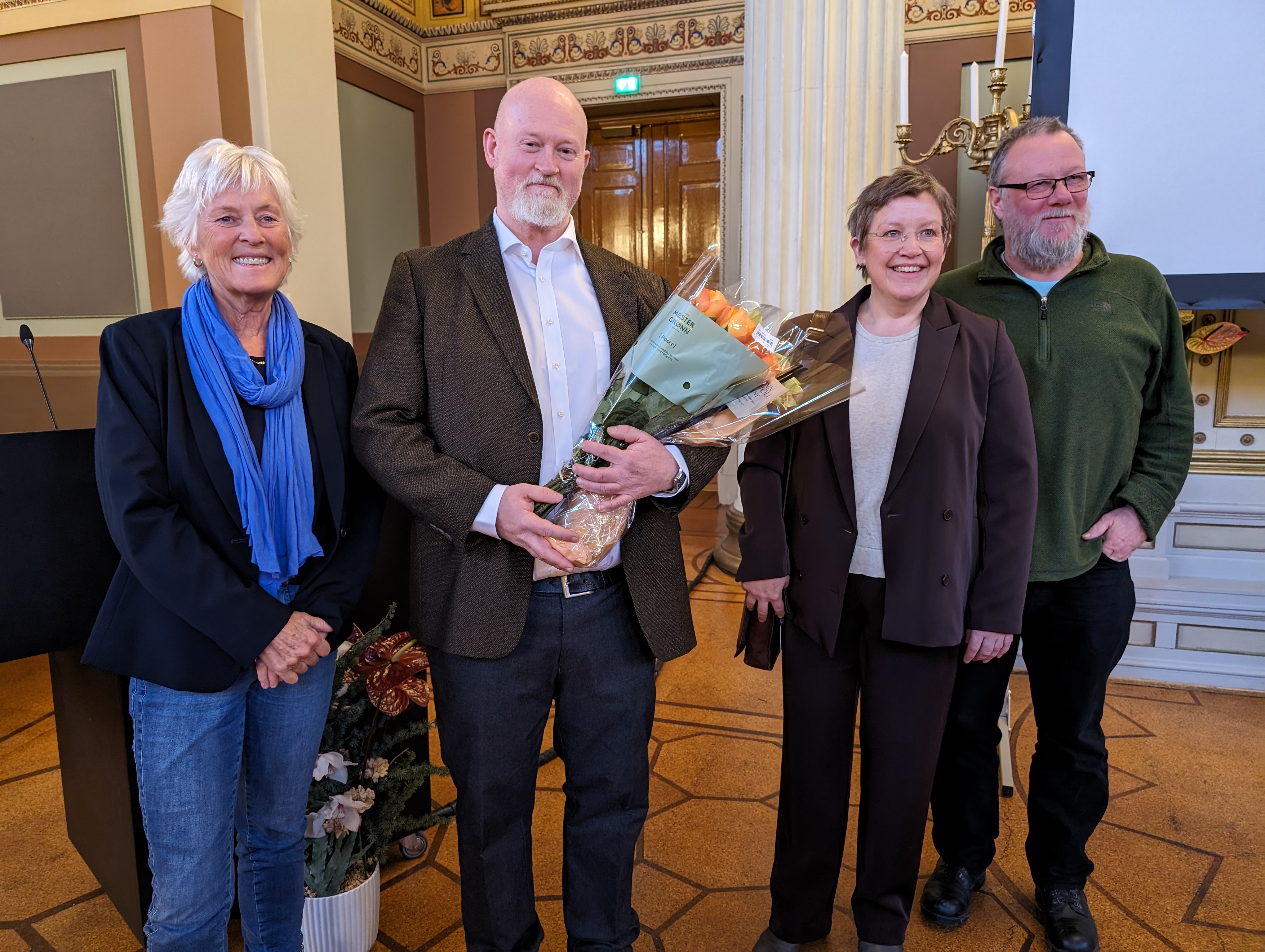 Pål Winnæss står med en farger blomsterbukett og smiler sammen med veilederne professor Heidi Mork Lomell (UiO) og seniorforsker Olve Krange (NINA)