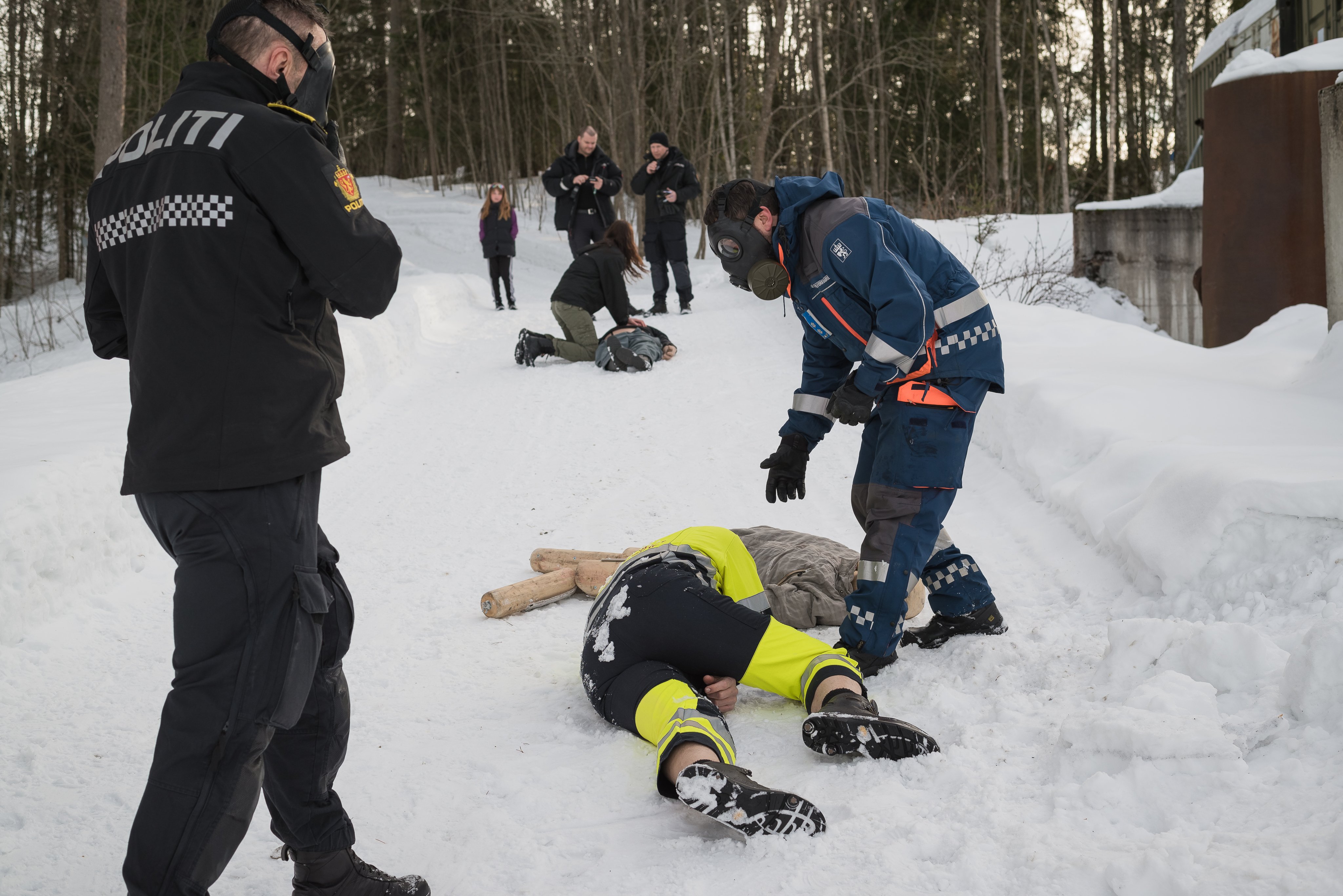 Politimann og en mann fra sivilforsvaret står med gassmasker over en markør i snøen. De deltar på en av øvelsene i regi av samvirkeutdanningen.