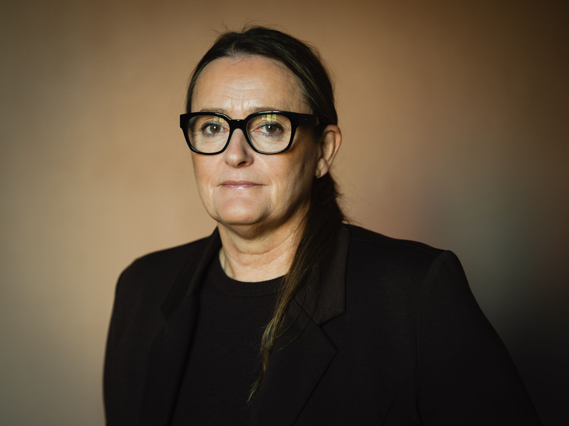 Portrett av kvinne i svart dress med sorte briller