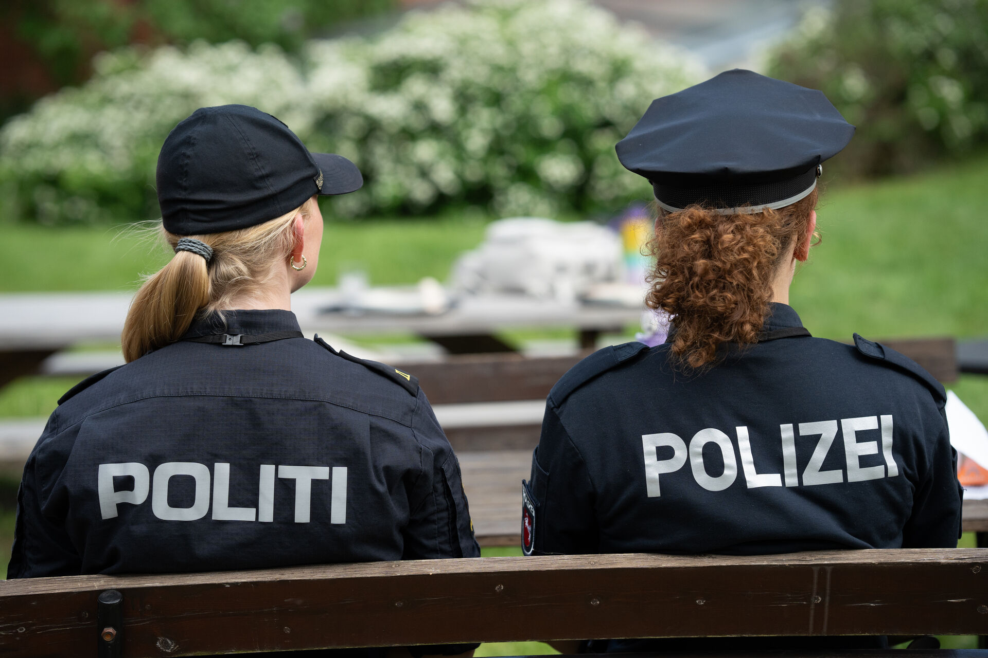 Two police officers, one Norwegian and one German with their back to the camera, sitting on a bench. 