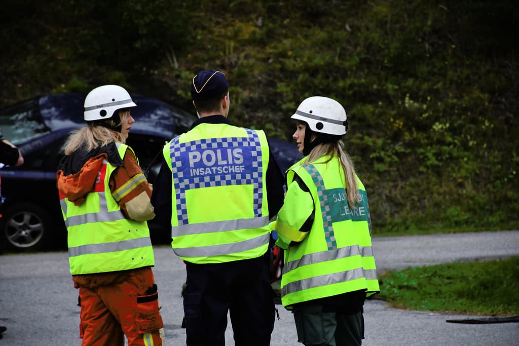 One police officer, one paramedic and an other service personell looking at the scene of an accident. 