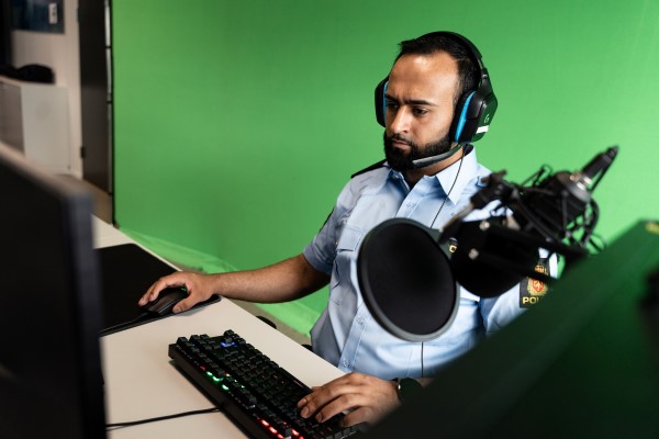 Umar Ditta sitter foran en PC. Han har på seg et headsett og ser inn i skjermen. 