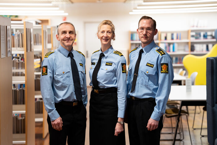 Tre personer i politiuniform inne i et bibliotek.