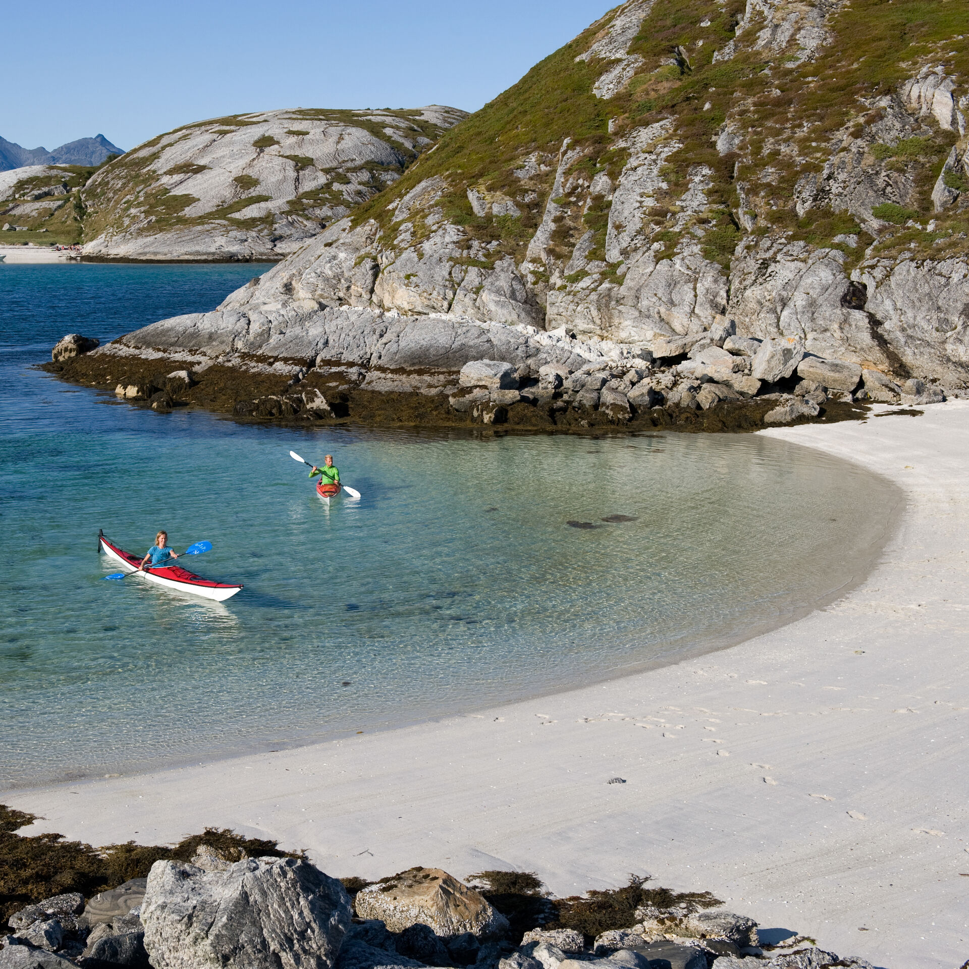 To kajakkpadlere padler opp mot en nydelig hvit sandstrand