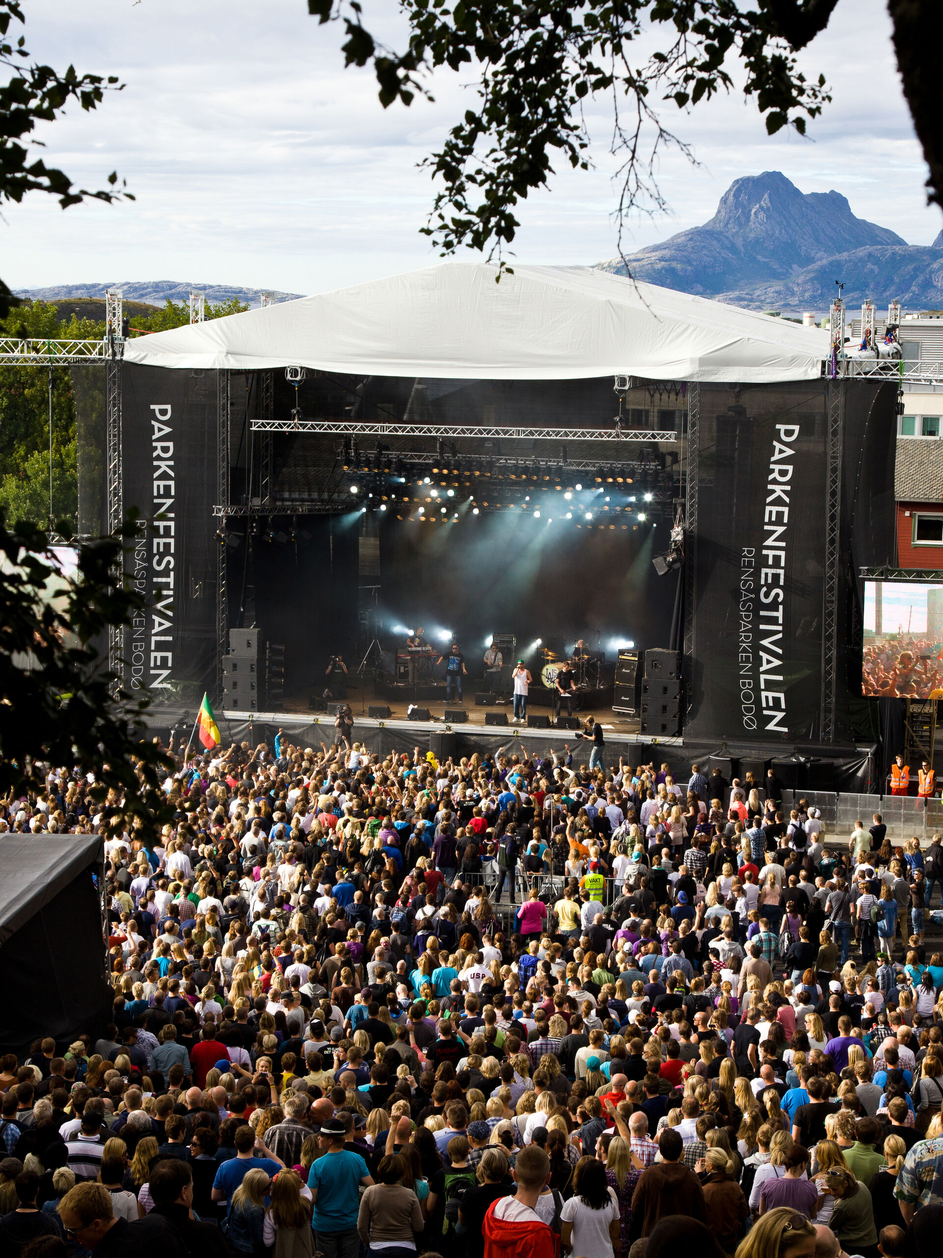 En artist spiller på en scene på Parkenfestival. Det er haugevis med publikummere til stede og fint vær. 