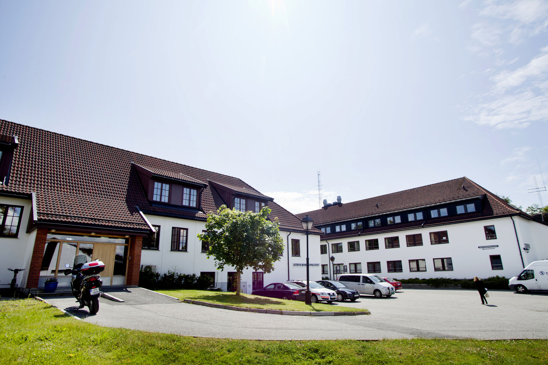   The picture shows two large, white buildings. Blue sky, grass and some trees.