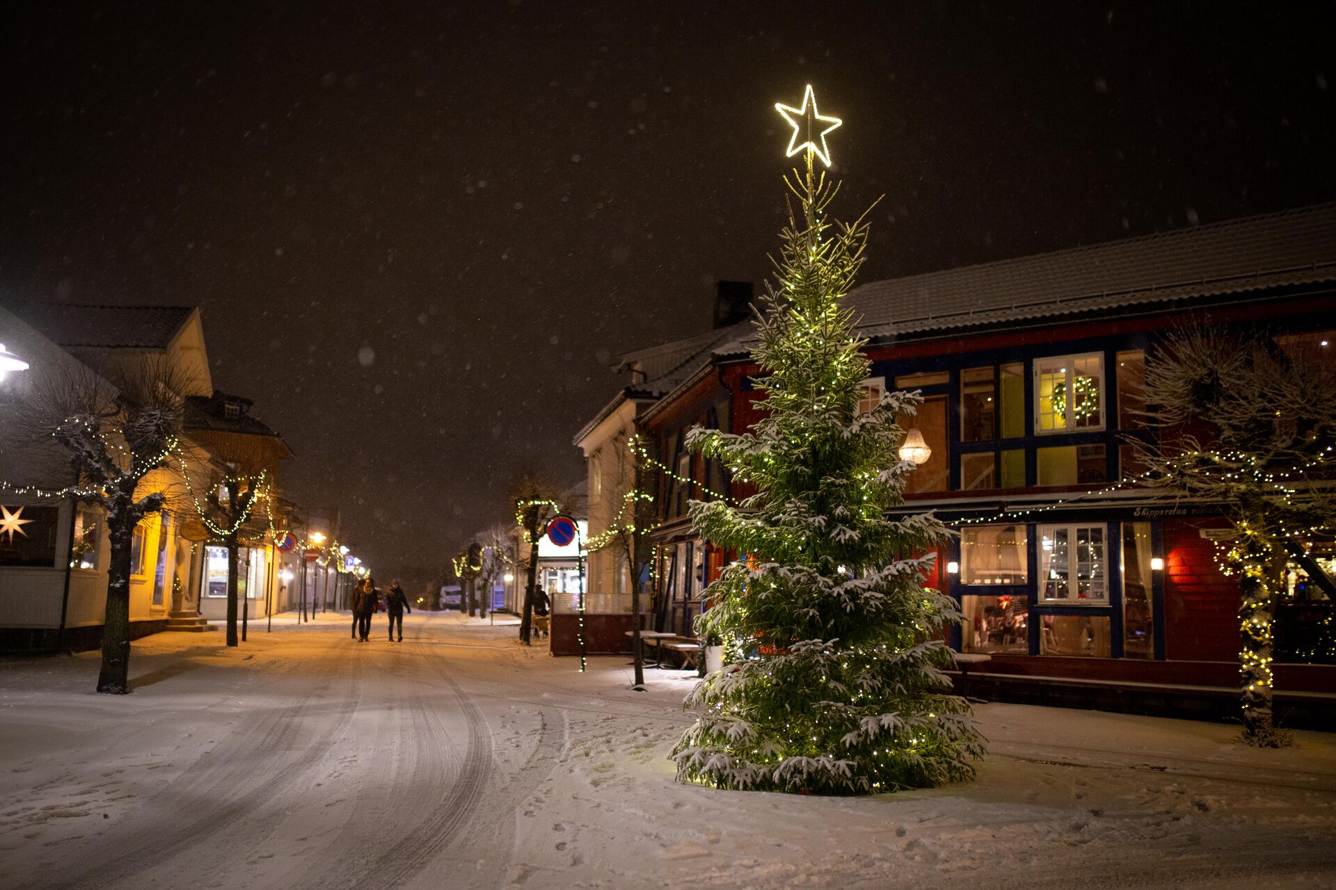 Julegate i Stavern. Et juletre lyser opp i midten og det er fine lysslynger på byggene og nedover gata.