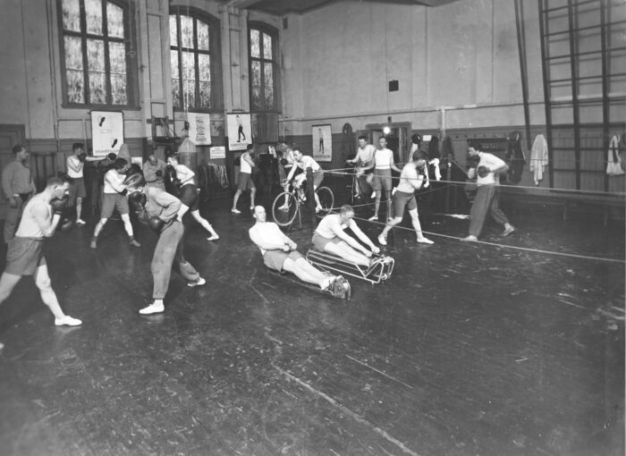 Gammel bilde som viser boksing og styrkeøvelser i gymsalen.