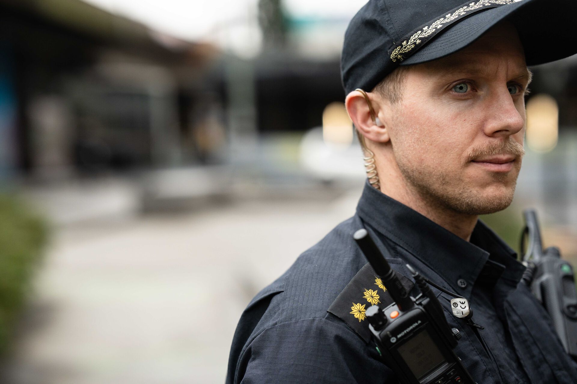 Portrett av politimann. Han står litt vendt bort fra kameraet, så man ser ham i profil. 