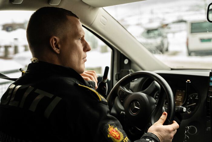 Bilde av politimann med kort hår bak rattet på en politibil.